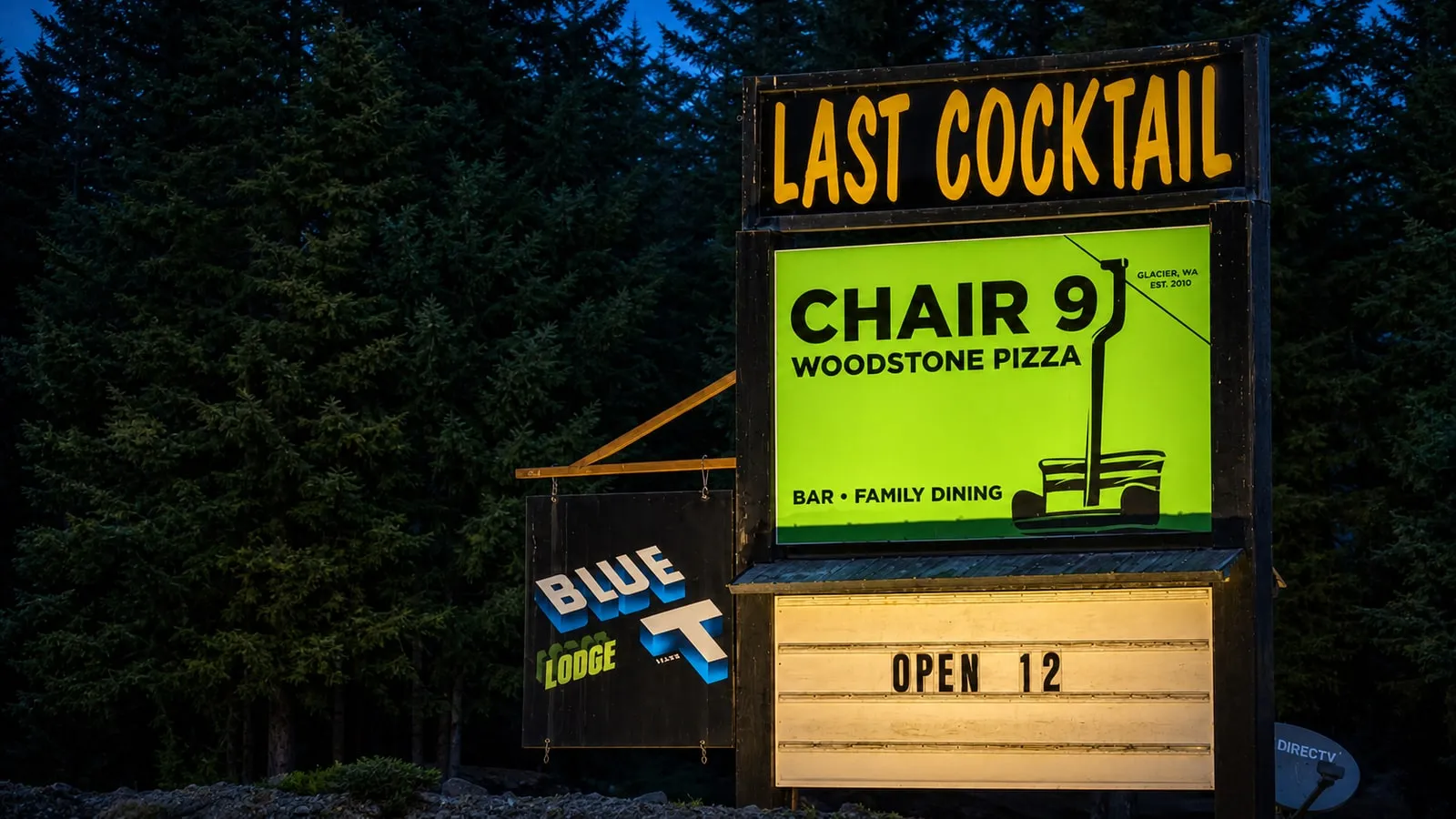 Chair 9’s roadside Woodstone Pizza, Bar and Family Dining sign lit at dusk