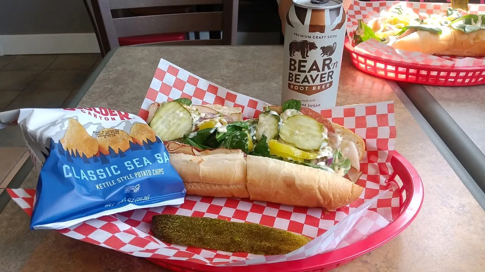 A deli sandwich, pickle, chips and root beer served at Feast 542