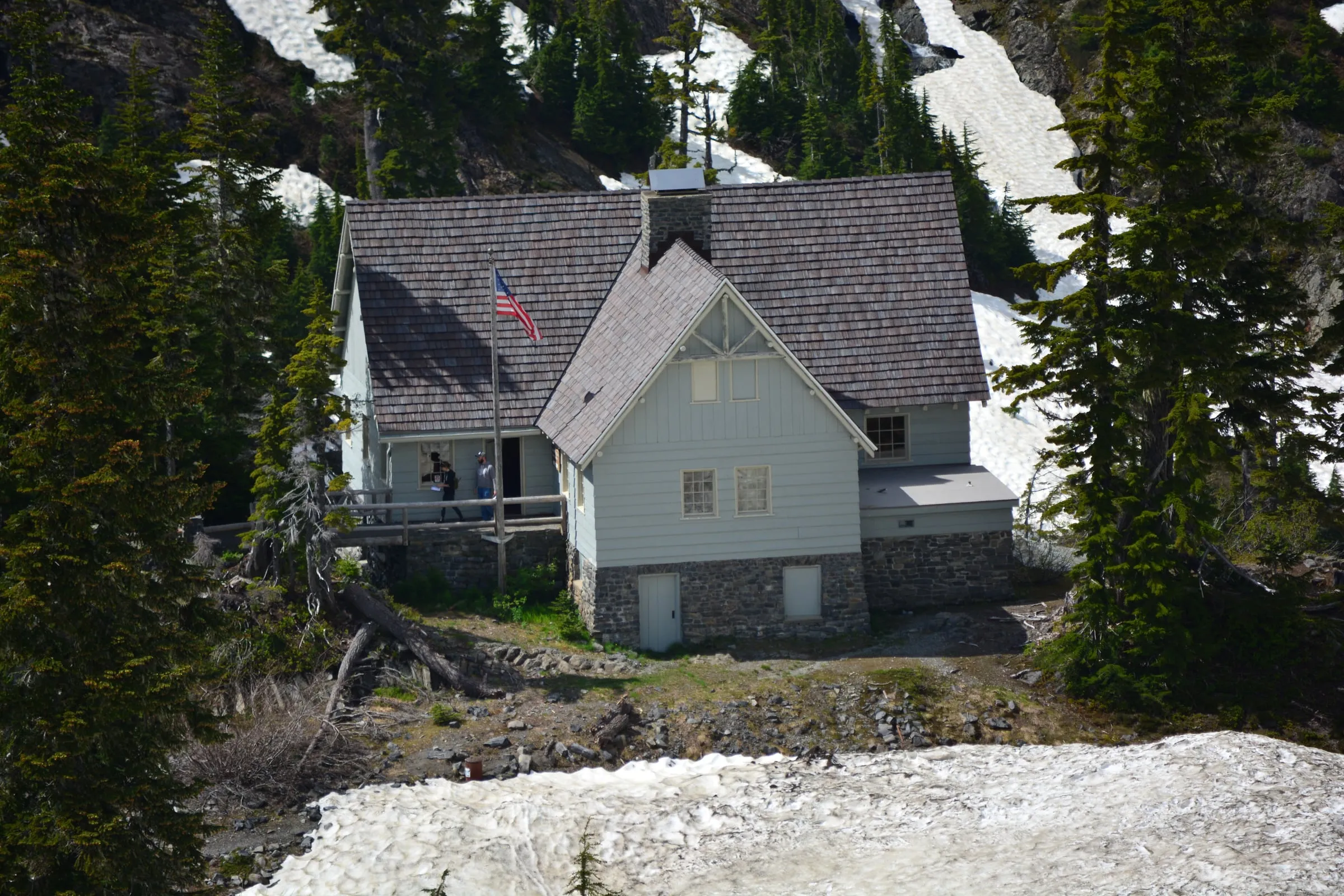 The stone-and-shingle Heather Meadows Visitor Center with snow lying on the slopes around it