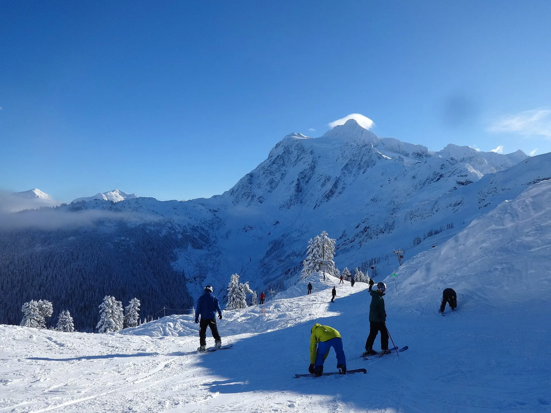 Skiers and snowboarders on a groomed run at Mt. Baker Ski Area with Mount Shuksan under midwinter snow behind