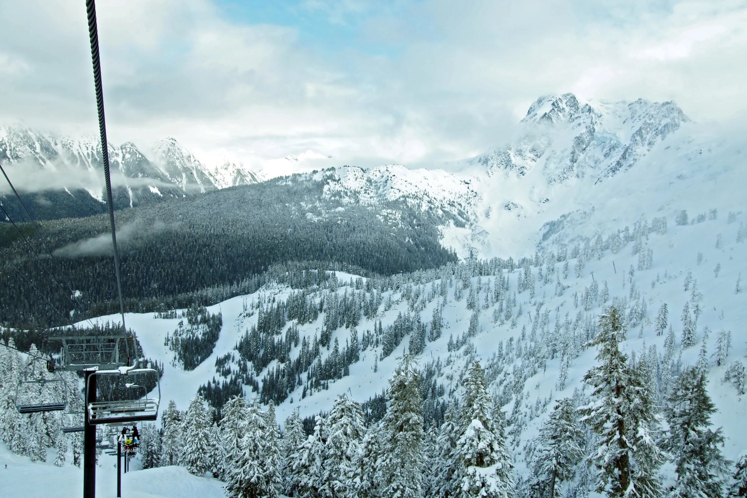 Chairlift carrying skiers above snow-covered runs at Mt. Baker Ski Area with Mount Shuksan behind