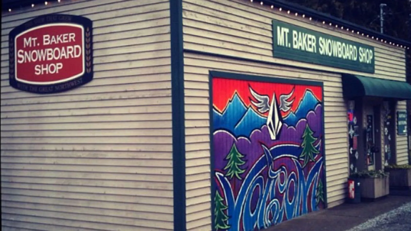 Mt. Baker Snowboard Shop exterior with its mountain-and-wave garage mural and shop signs