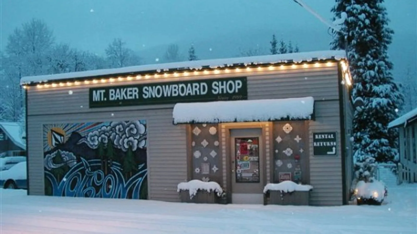 Mt. Baker Snowboard Shop storefront and painted garage mural in fresh snow in Glacier, Washington
