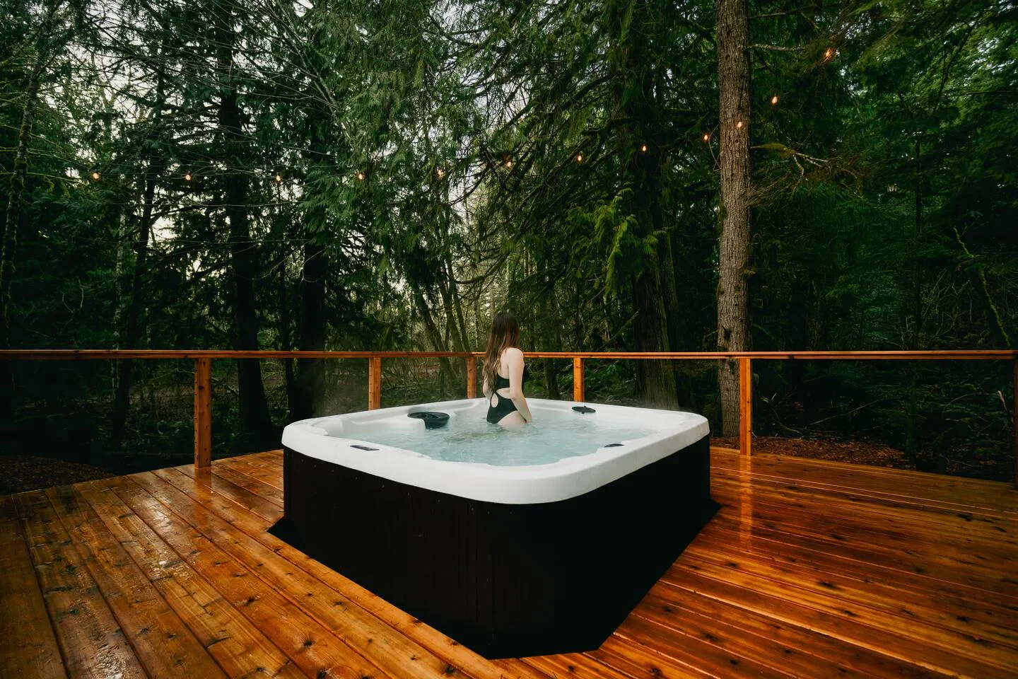 Hot tub on the wooden deck beside the black A-frame cabin