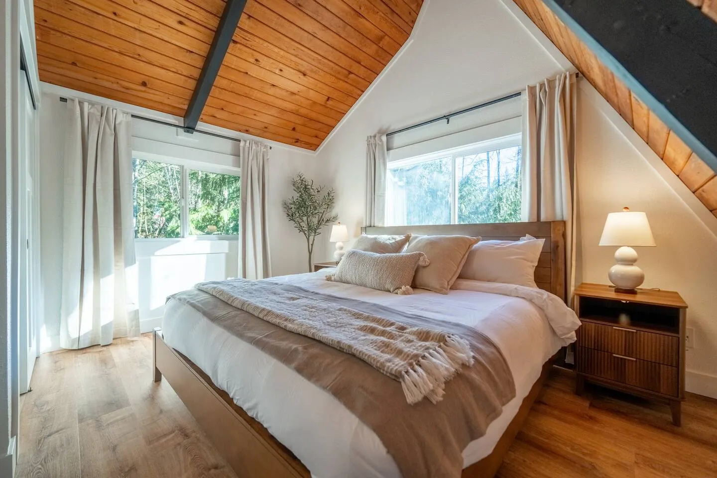 Queen bedroom with vaulted wood ceiling and window light