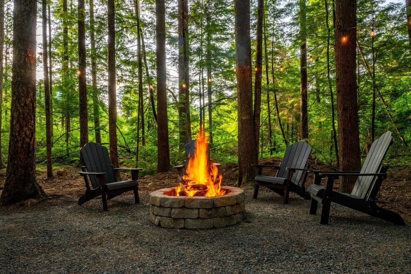 Stone fire pit with Adirondack chairs in the forest
