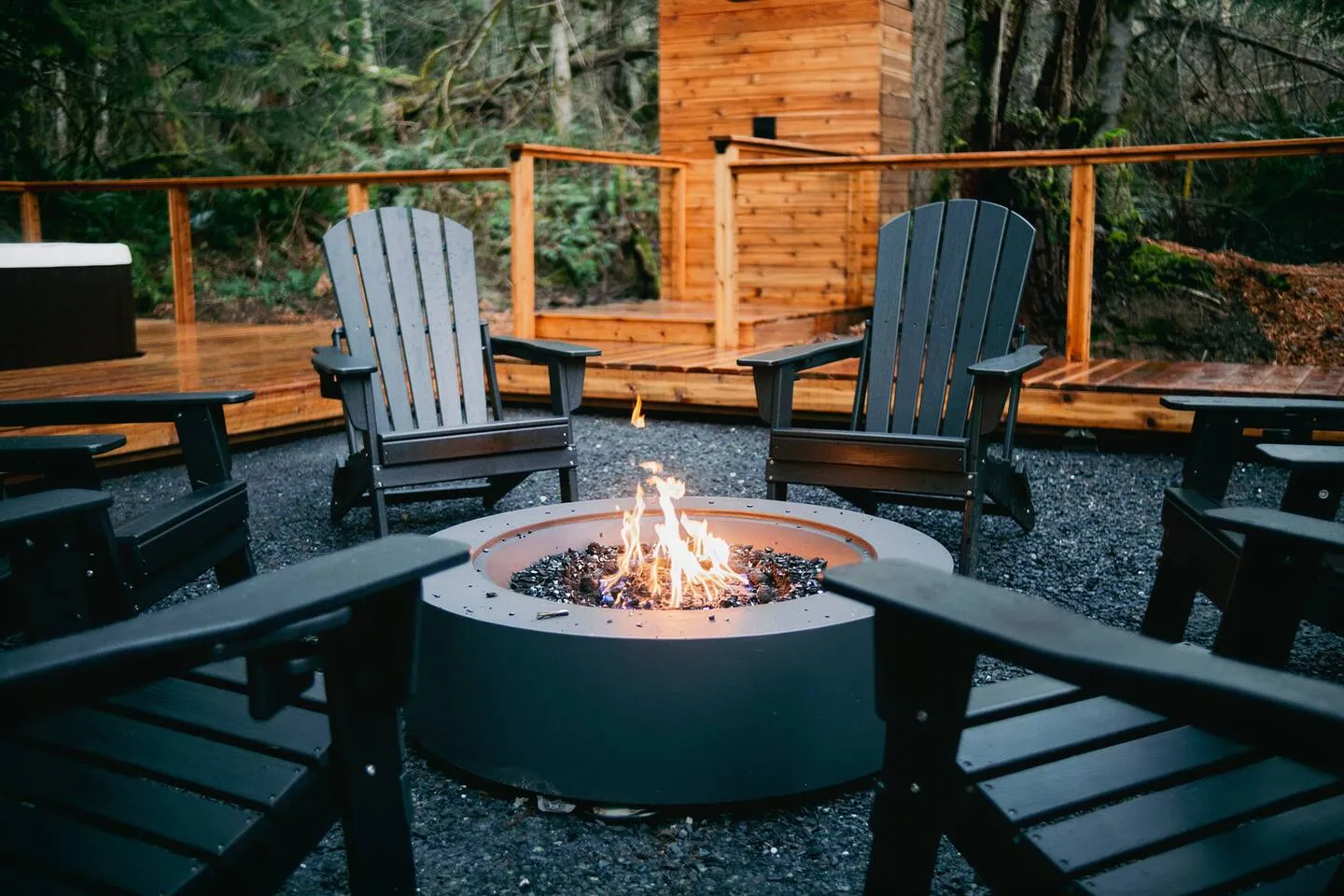 Gas fire pit surrounded by Adirondack chairs at night