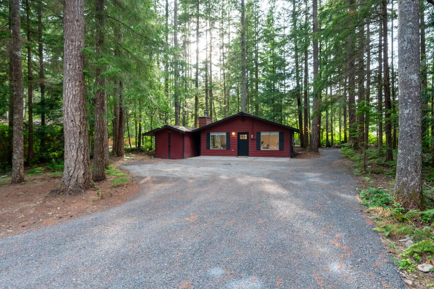 Gravel driveway leading to the red cabin in the woods