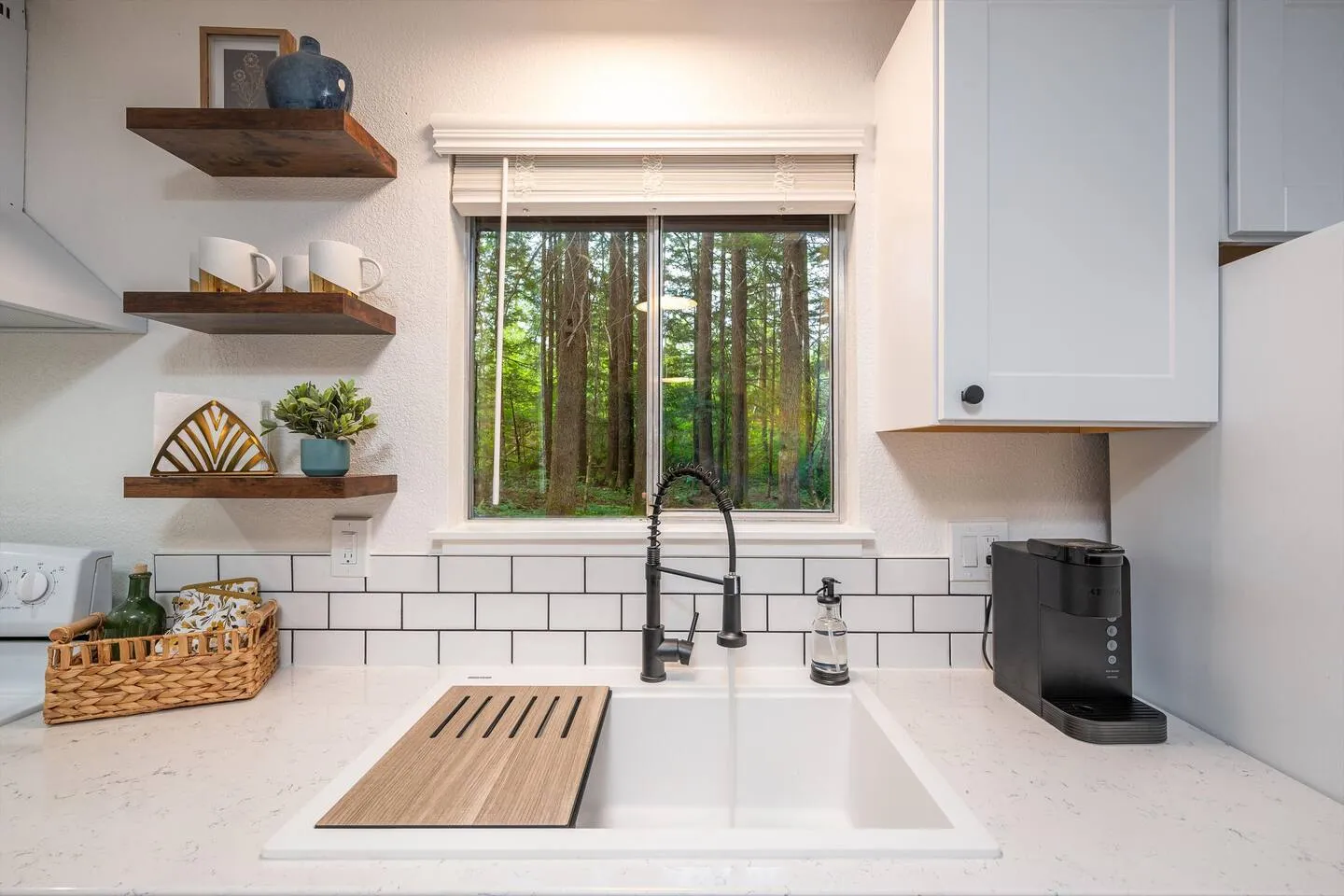 White farmhouse kitchen with subway tile and forest view