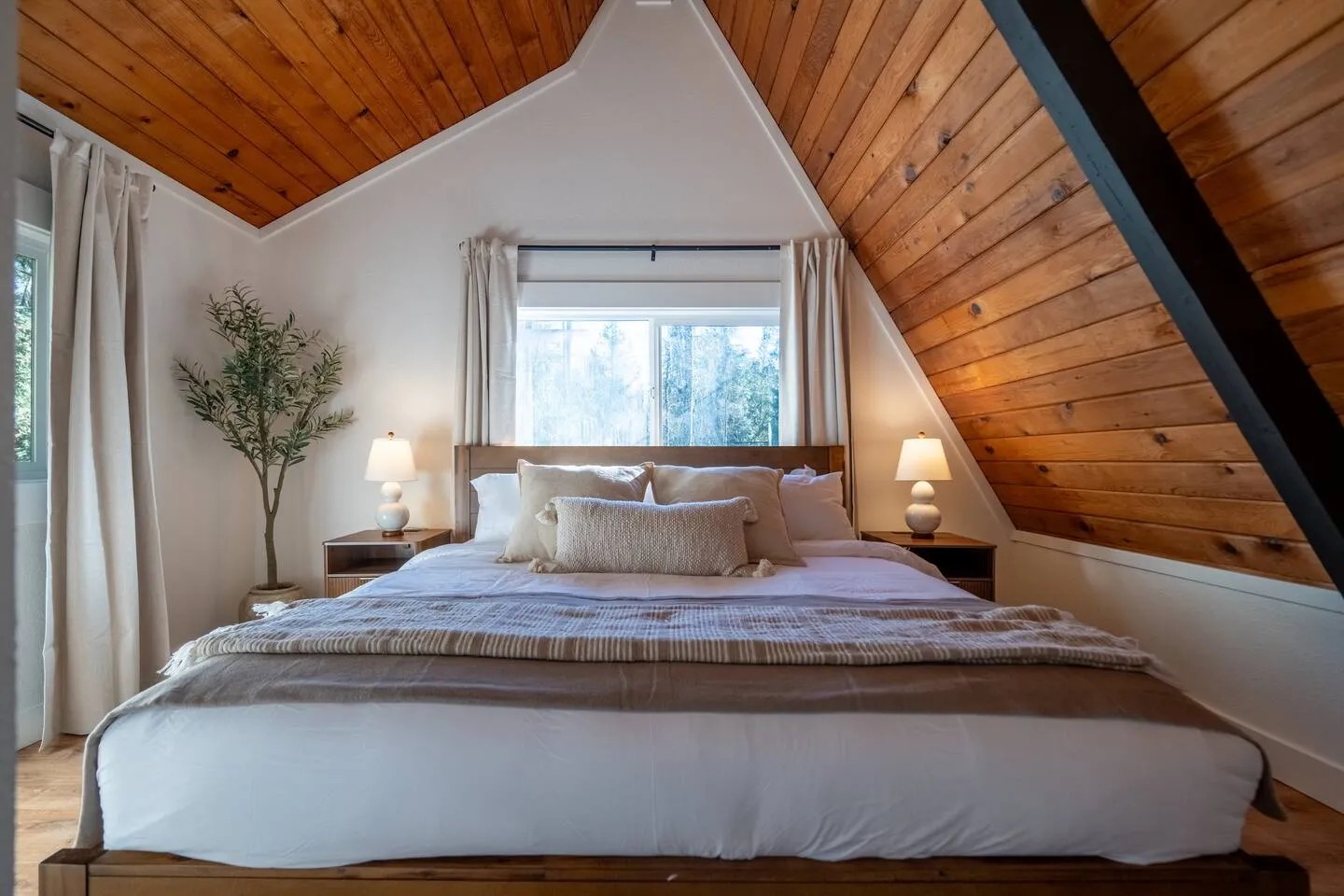 King bedroom with wood-paneled ceiling and soft linens