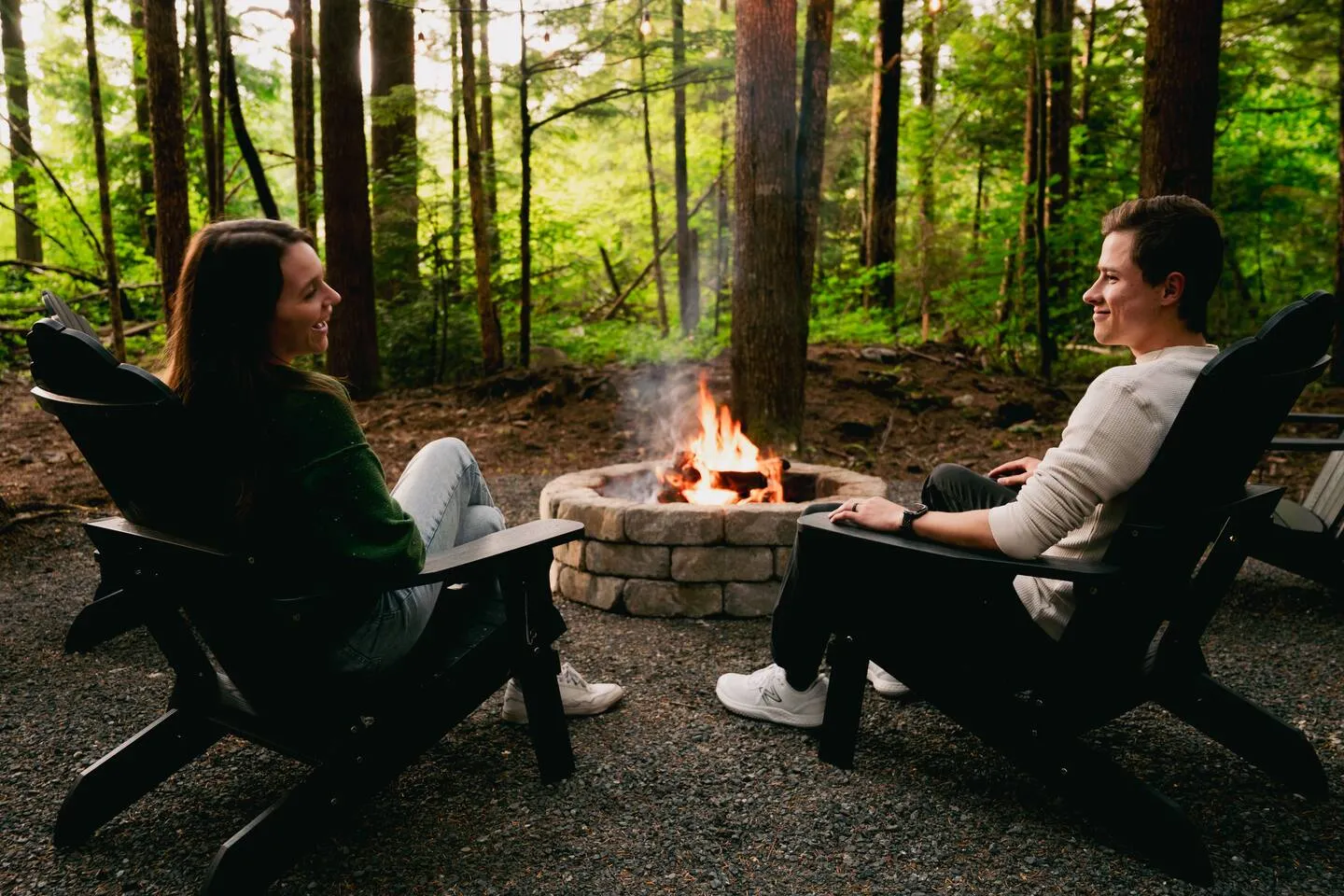 Couple relaxing by the fire pit among the trees