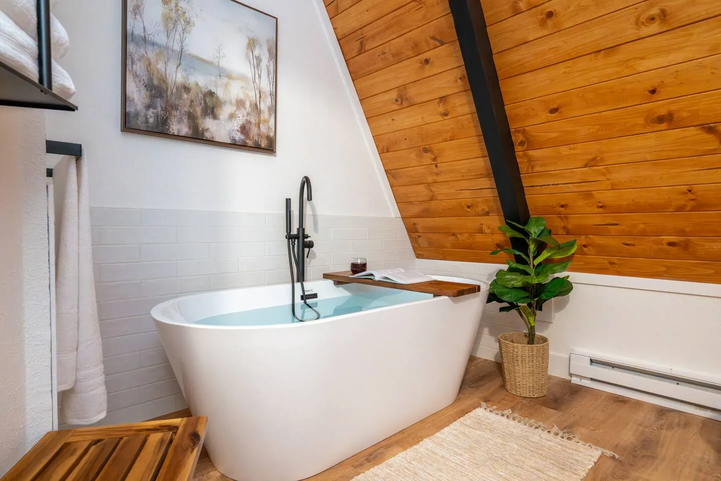 Free-standing soaking tub beside warm wood paneling