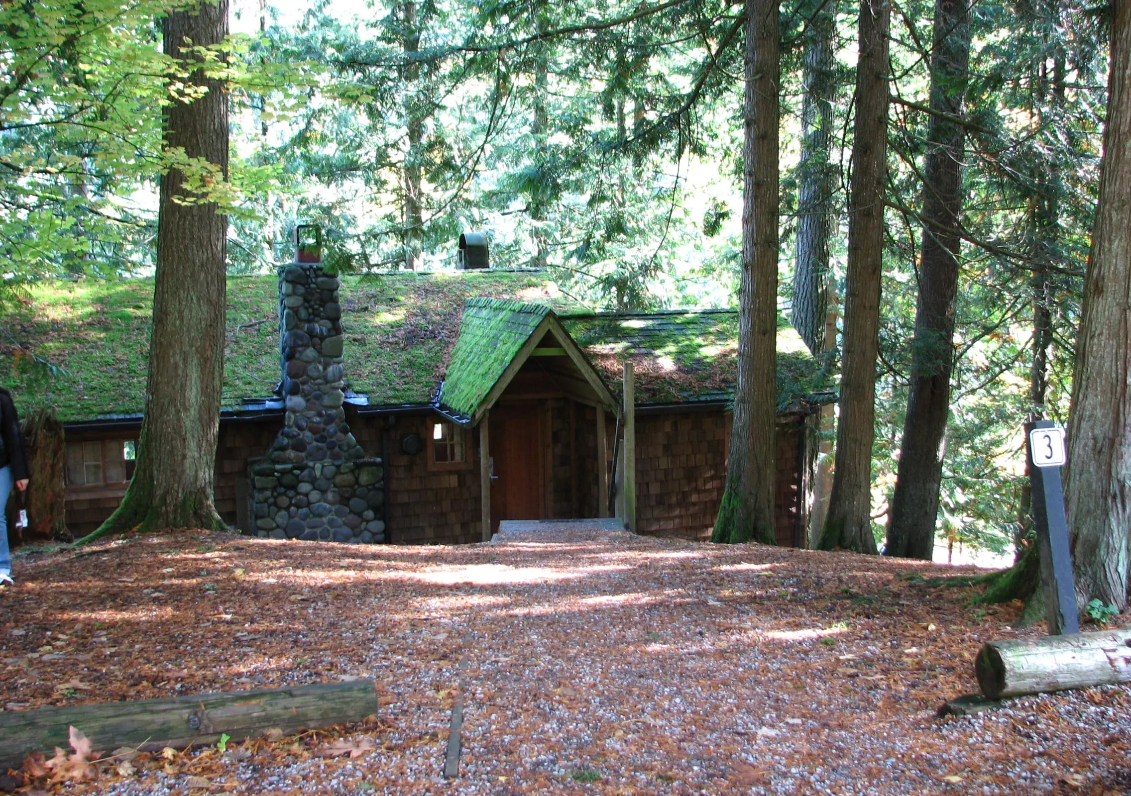 A cedar-shingled 1940s rental cabin with a river-rock chimney at Silver Lake Park